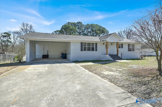 ranch-style home featuring a carport, fence, concrete driveway, and brick siding