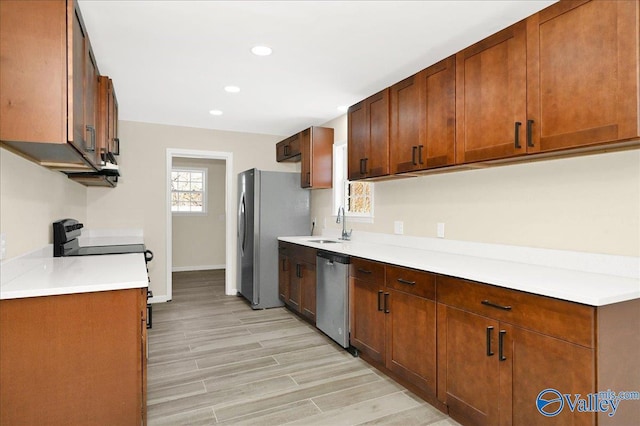 kitchen featuring light countertops, stainless steel appliances, light wood-style floors, a sink, and recessed lighting