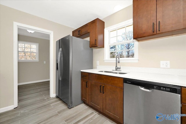 kitchen with stainless steel appliances, light wood-style floors, light countertops, and a sink