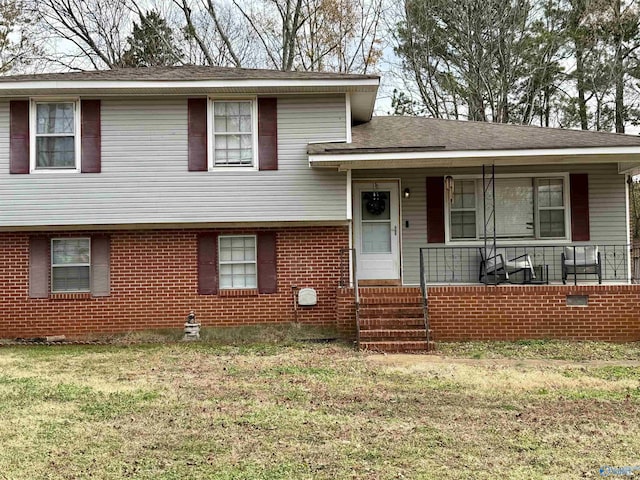 tri-level home featuring covered porch and a front yard