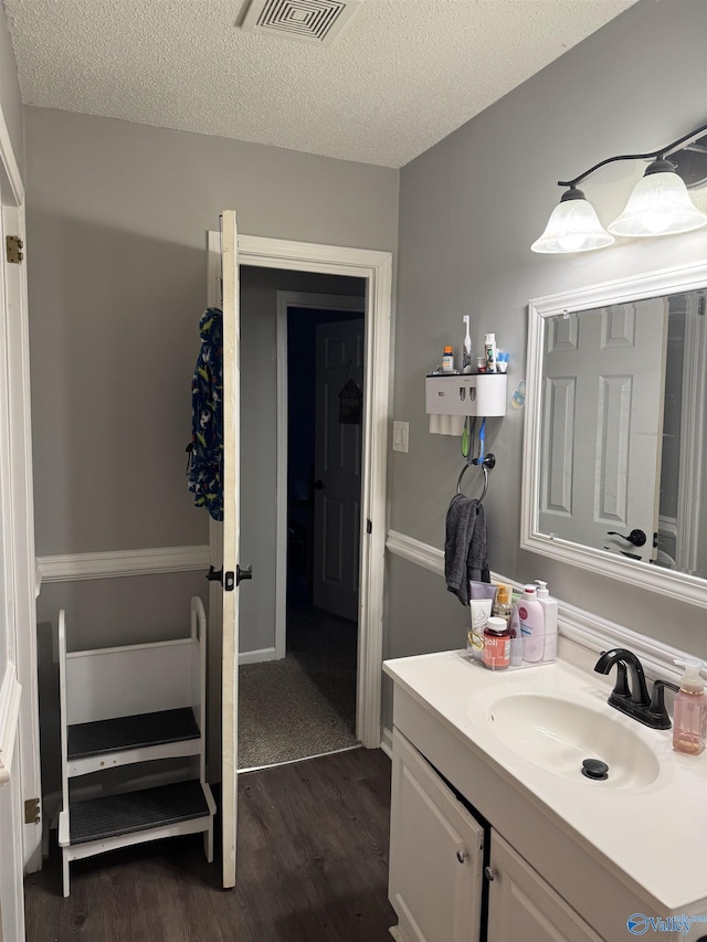 bathroom featuring vanity, wood-type flooring, and a textured ceiling