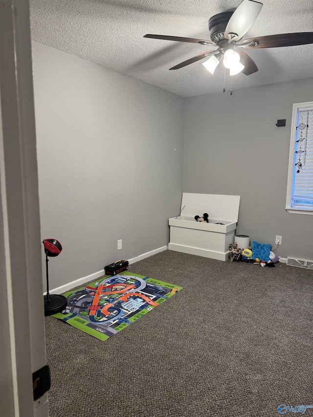 rec room with carpet, ceiling fan, and a textured ceiling