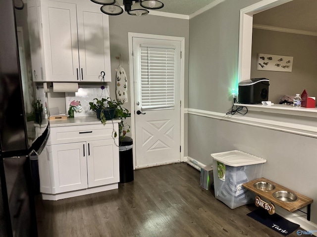 kitchen featuring white cabinets, dark hardwood / wood-style flooring, stainless steel refrigerator, and ornamental molding