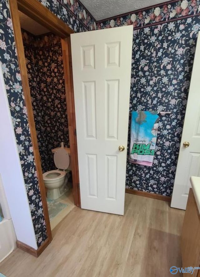 bathroom featuring toilet, a textured ceiling, and hardwood / wood-style flooring