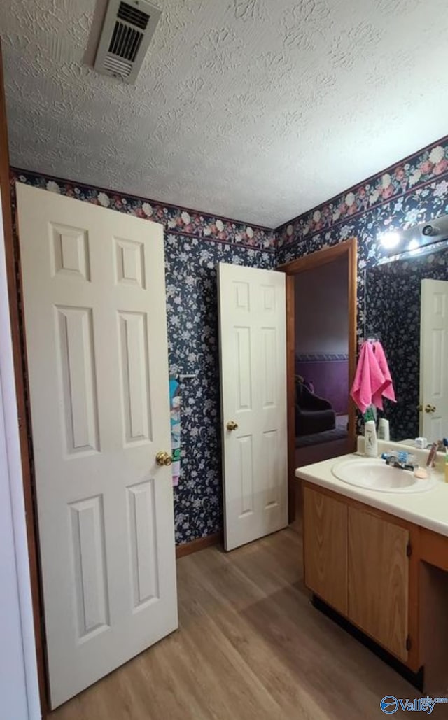 bathroom featuring vanity, hardwood / wood-style floors, and a textured ceiling