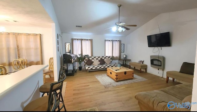 living room with heating unit, ceiling fan, hardwood / wood-style floors, and lofted ceiling