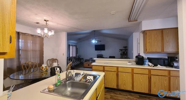 kitchen with pendant lighting, lofted ceiling, ceiling fan with notable chandelier, sink, and dark hardwood / wood-style flooring