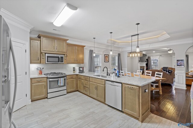 kitchen featuring kitchen peninsula, stainless steel appliances, hanging light fixtures, and sink