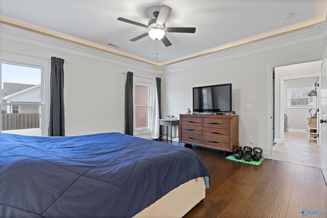 bedroom featuring ceiling fan, dark hardwood / wood-style floors, crown molding, and multiple windows