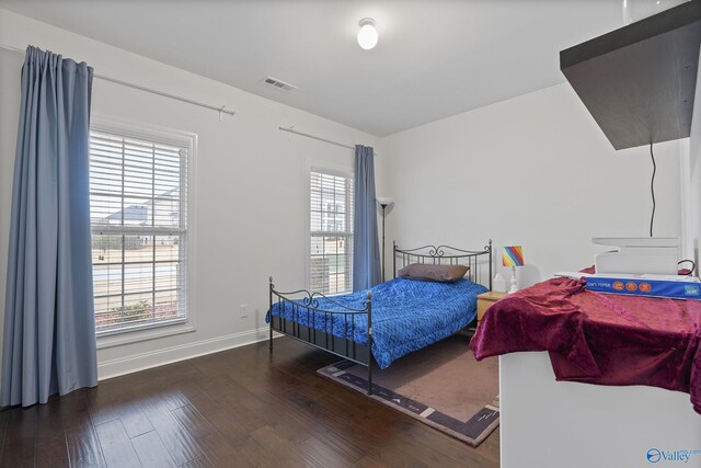 bedroom with multiple windows and dark hardwood / wood-style flooring