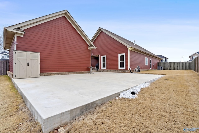 rear view of property featuring a storage unit, cooling unit, and a patio