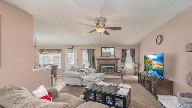 living room featuring a glass covered fireplace, carpet, a ceiling fan, and a textured ceiling