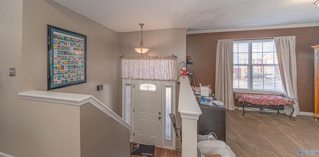 foyer featuring a textured ceiling, crown molding, baseboards, and carpet floors