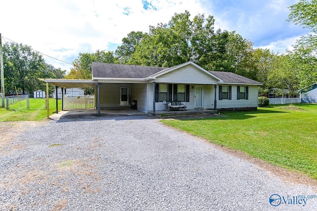 ranch-style house with a front yard, gravel driveway, an attached carport, and fence