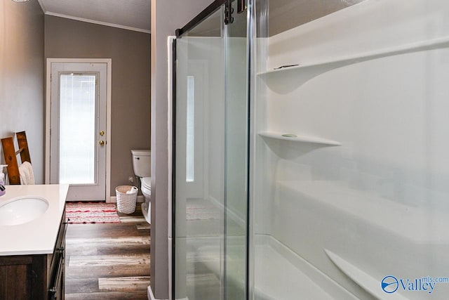 bathroom with vanity, crown molding, toilet, a shower with door, and hardwood / wood-style floors