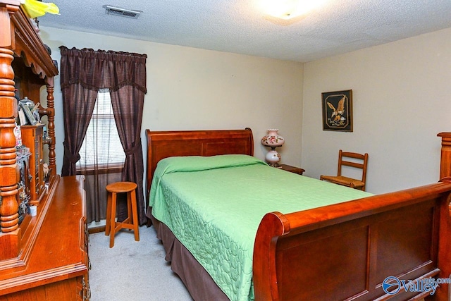 bedroom with a textured ceiling and light carpet