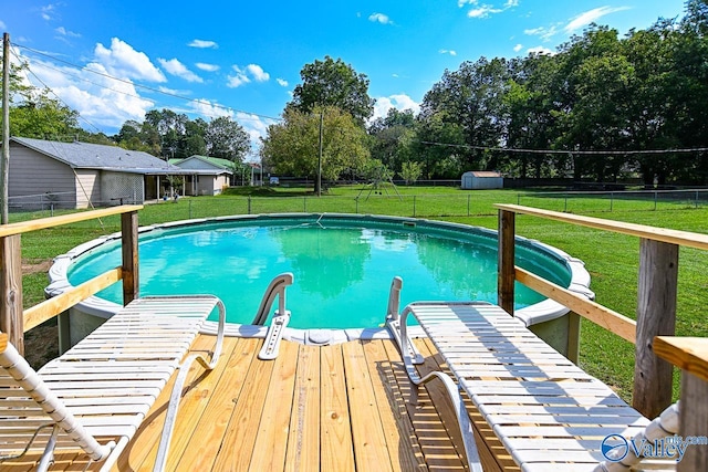 view of pool with a lawn and a storage unit