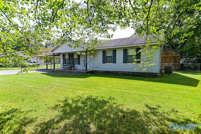 single story home featuring a storage unit, a front lawn, central AC unit, and covered porch