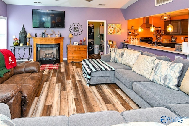 living room with stacked washer and clothes dryer and wood-type flooring