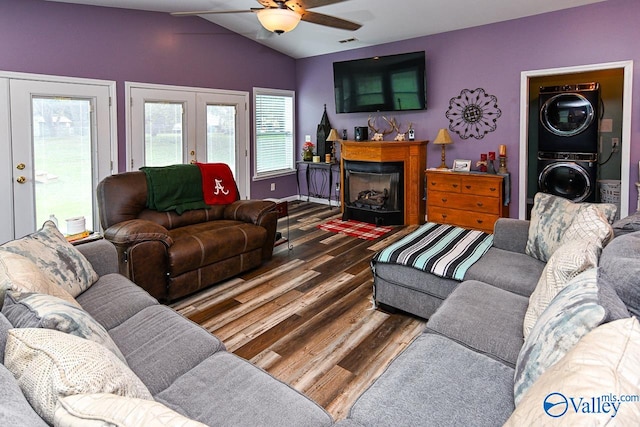 living room featuring vaulted ceiling, wood-type flooring, stacked washer and dryer, ceiling fan, and french doors