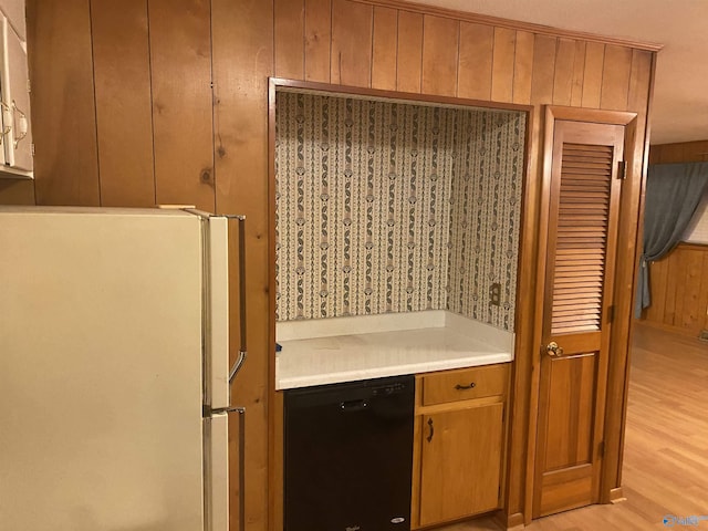 kitchen featuring white fridge, light hardwood / wood-style flooring, black dishwasher, and wood walls