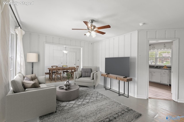 living room featuring hardwood / wood-style flooring, ceiling fan, and sink