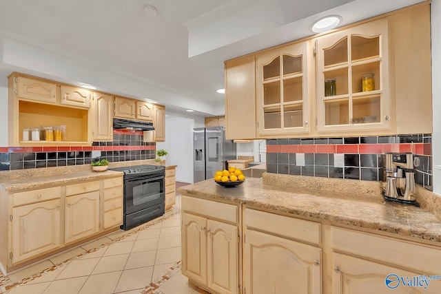 kitchen featuring black range with electric stovetop, under cabinet range hood, stainless steel fridge, light tile patterned floors, and decorative backsplash