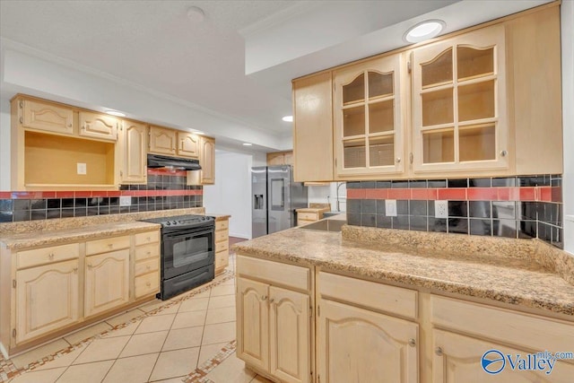 kitchen featuring stainless steel refrigerator with ice dispenser, under cabinet range hood, black / electric stove, light tile patterned flooring, and glass insert cabinets