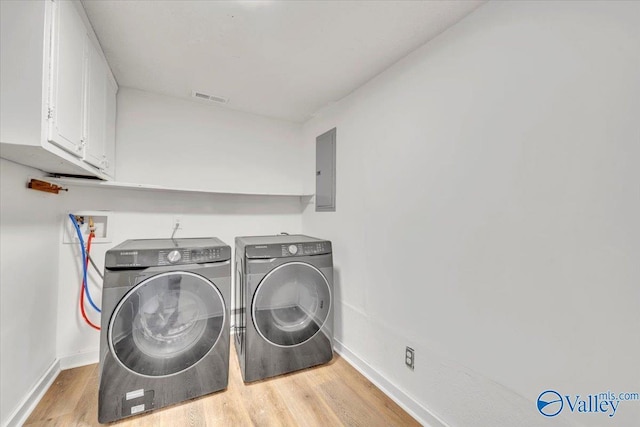 laundry area featuring visible vents, electric panel, wood finished floors, cabinet space, and independent washer and dryer