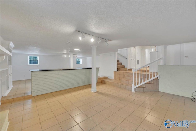 basement featuring tile patterned floors, a textured ceiling, and stairs