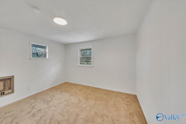 carpeted spare room featuring heating unit and a textured ceiling