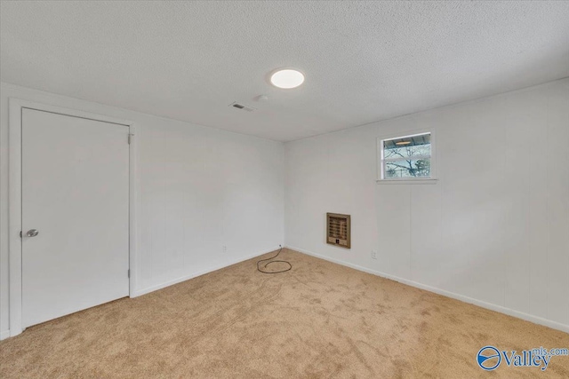 spare room with heating unit, visible vents, a textured ceiling, and carpet floors