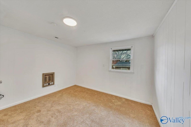 carpeted spare room with heating unit, visible vents, baseboards, and a textured ceiling