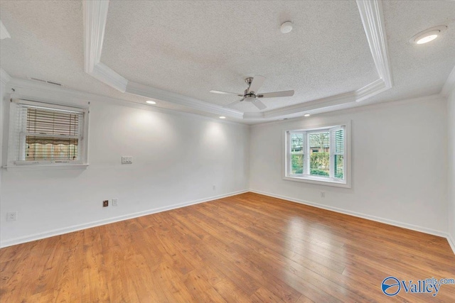 spare room with crown molding, a textured ceiling, a raised ceiling, and hardwood / wood-style floors