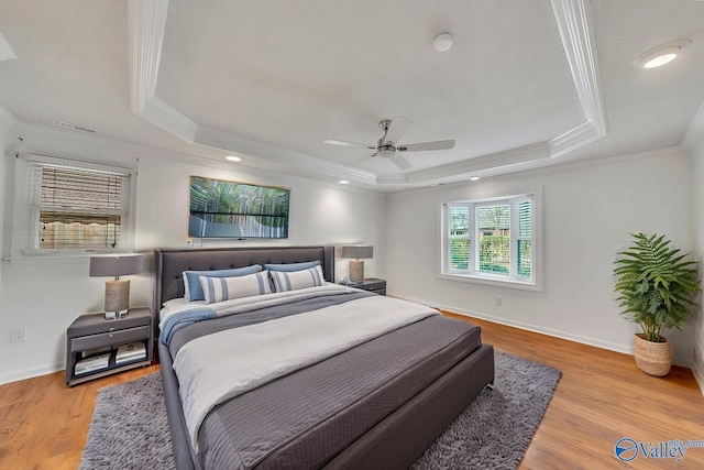 bedroom featuring crown molding, ceiling fan, baseboards, wood finished floors, and a raised ceiling