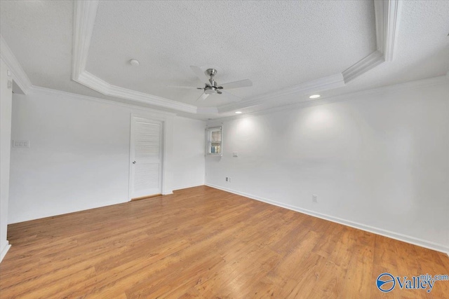 spare room with a tray ceiling, a textured ceiling, ceiling fan, and light wood finished floors