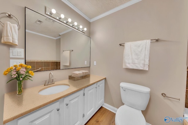 bathroom with toilet, ornamental molding, wood finished floors, baseboards, and vanity