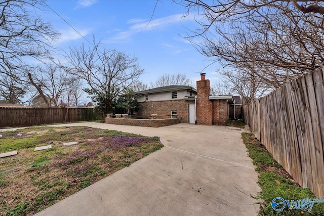 view of yard featuring a patio, concrete driveway, and a fenced backyard