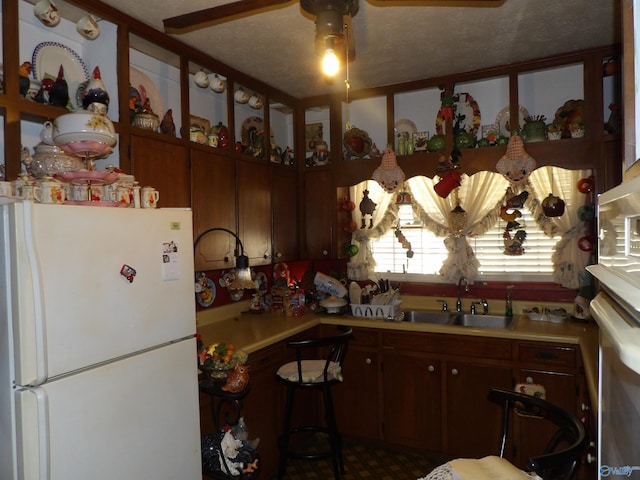 kitchen with stainless steel oven, sink, white refrigerator, a textured ceiling, and ceiling fan