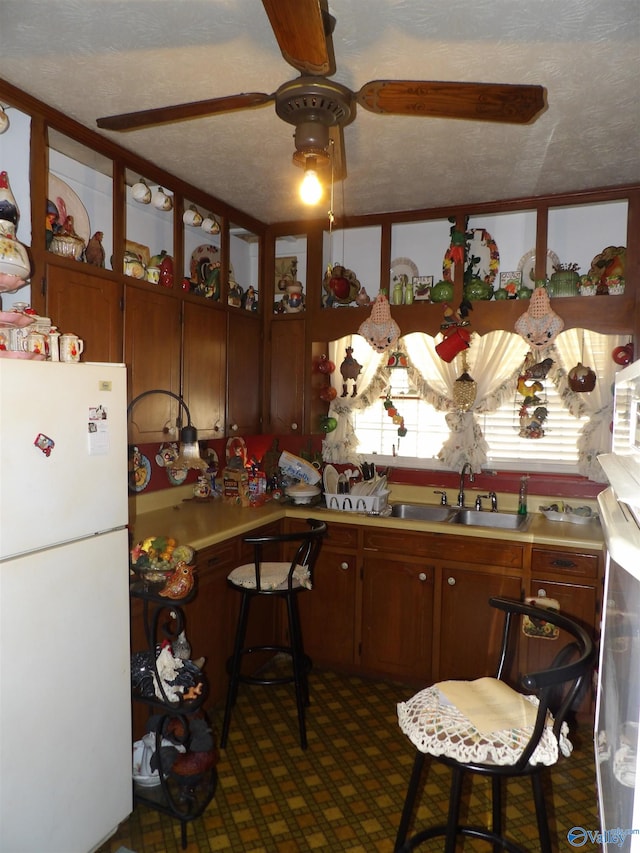 kitchen with white fridge, a textured ceiling, and sink