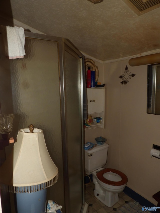 bathroom with tile patterned floors, a textured ceiling, toilet, and walk in shower