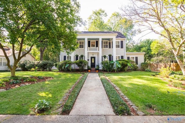 greek revival inspired property with a balcony and a front lawn