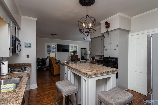 kitchen featuring a center island, dark hardwood / wood-style floors, an inviting chandelier, black appliances, and crown molding