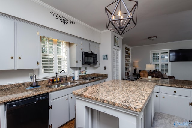 kitchen featuring a kitchen island, crown molding, black appliances, decorative light fixtures, and sink