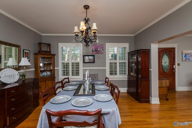 dining room featuring an inviting chandelier, a wealth of natural light, light hardwood / wood-style floors, and crown molding