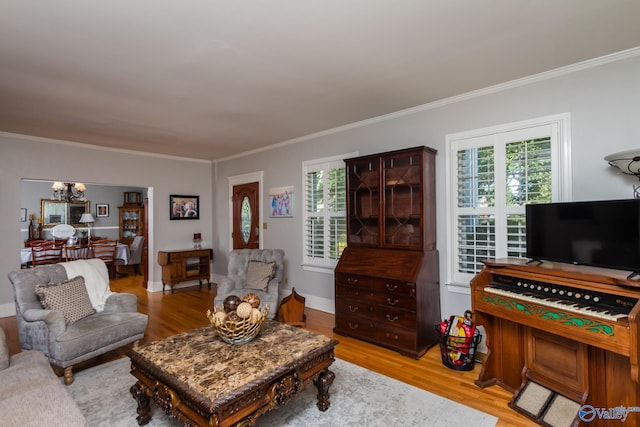 living room with ornamental molding, light hardwood / wood-style flooring, and a notable chandelier