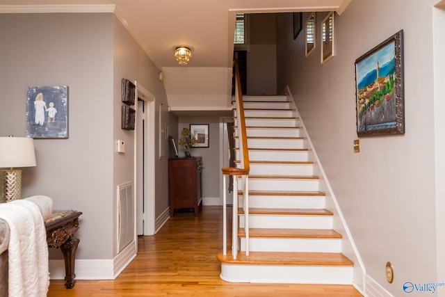 staircase with ornamental molding and wood-type flooring