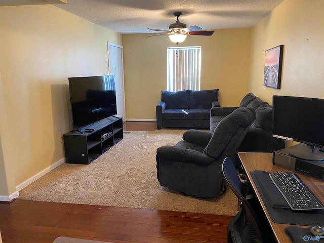 living area featuring a ceiling fan, a textured ceiling, baseboards, and wood finished floors