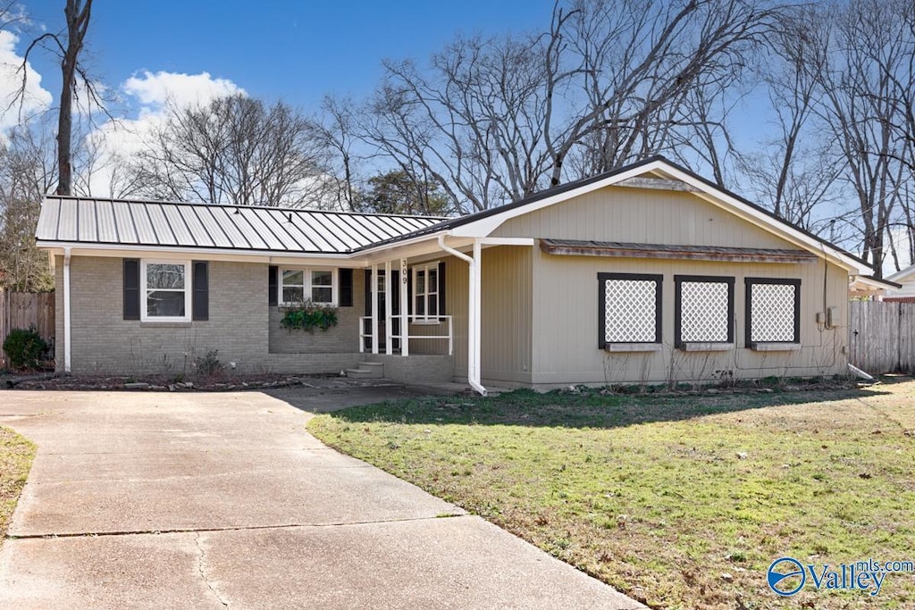 ranch-style house with a front yard, metal roof, brick siding, and fence