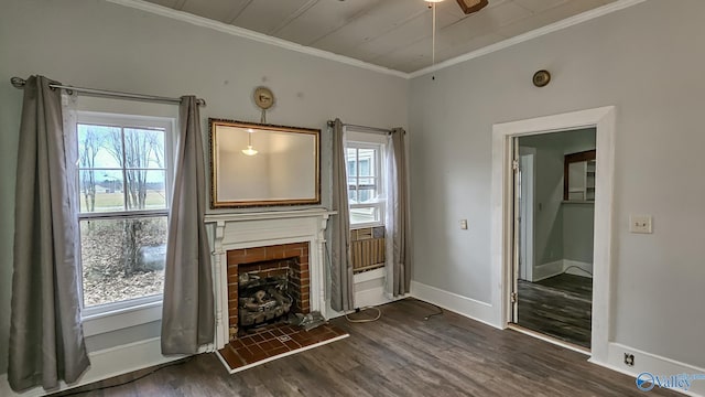 unfurnished living room featuring crown molding, a brick fireplace, dark wood-type flooring, and ceiling fan